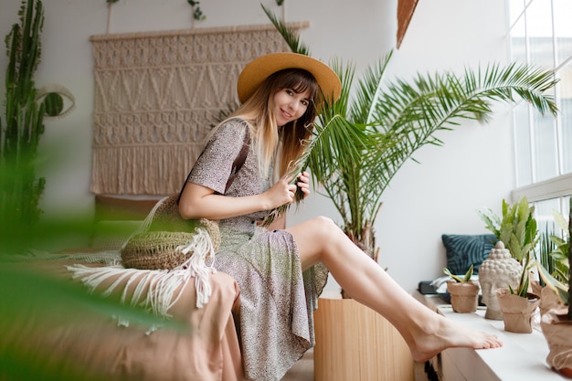 Bonita mujer sentada en la cama en su apartamento boho