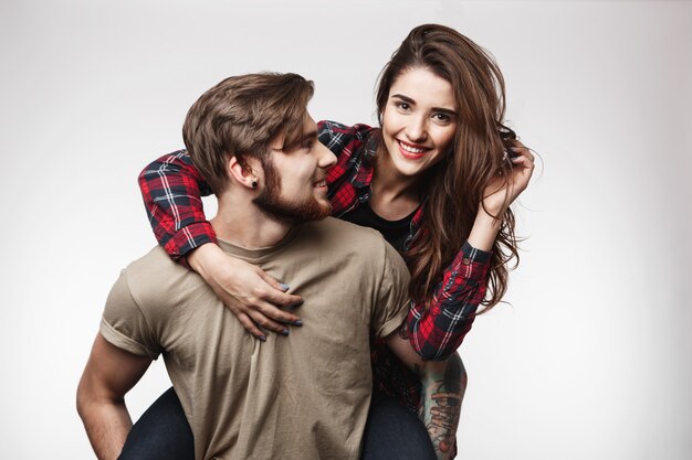 Bonita mujer sentada sobre la espalda del hombre, sonriendo