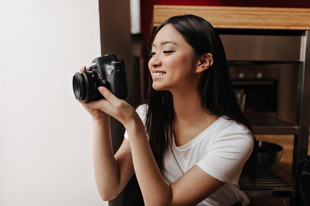 Bonita mujer en top blanco está sonriendo y tomando fotografías en el frente