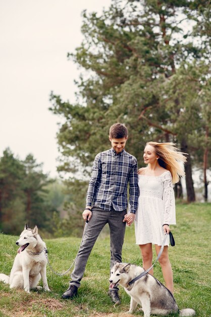 Bonita pareja en un bosque de verano con perros.