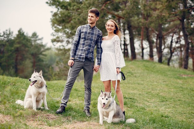 Bonita pareja en un bosque de verano con perros.