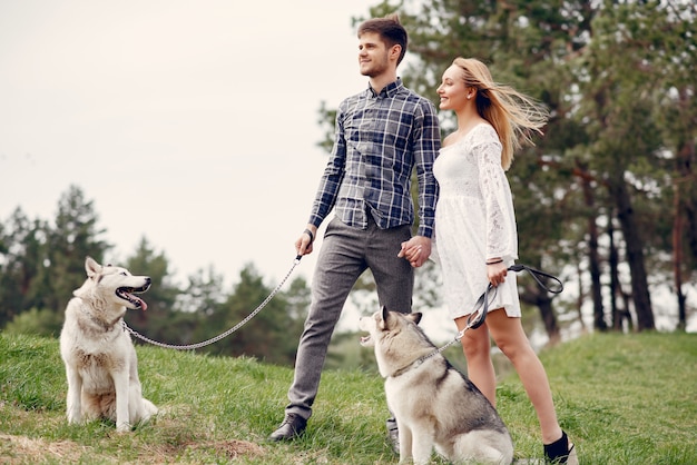 Bonita pareja en un bosque de verano con perros.