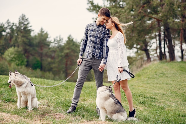 Bonita pareja en un bosque de verano con perros.