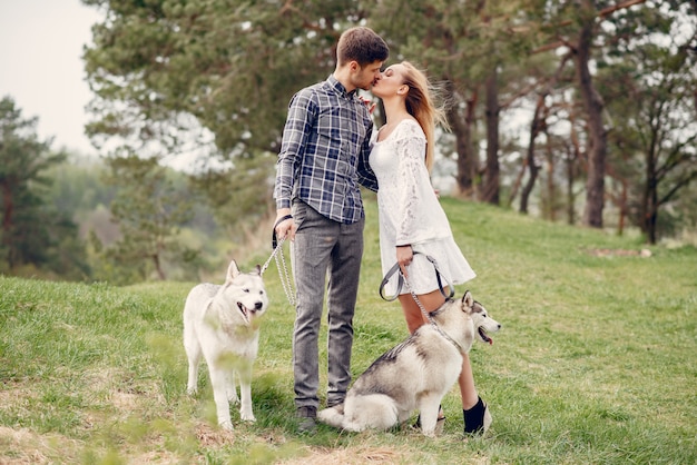 Bonita pareja en un bosque de verano con perros.