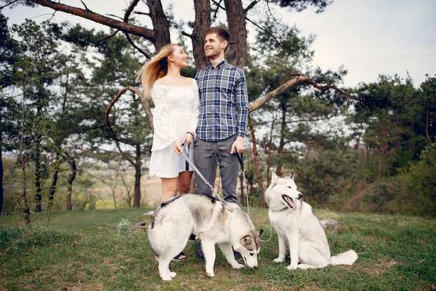 Bonita pareja en un bosque de verano con perros.