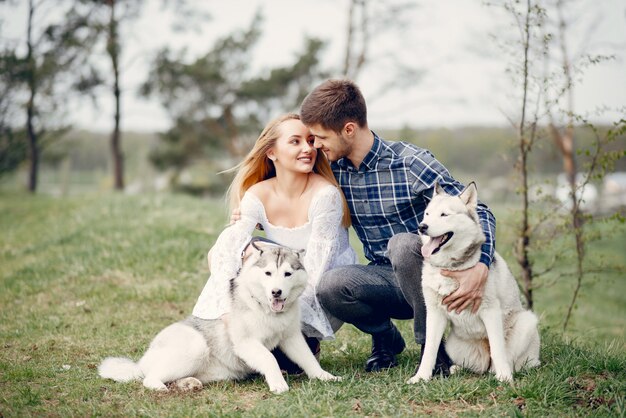 Bonita pareja en un bosque de verano con perros.