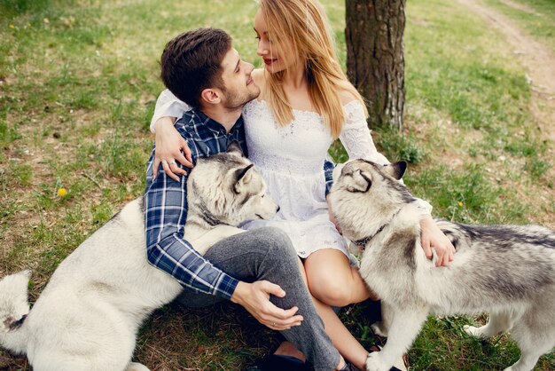 Bonita pareja en un bosque de verano con perros.