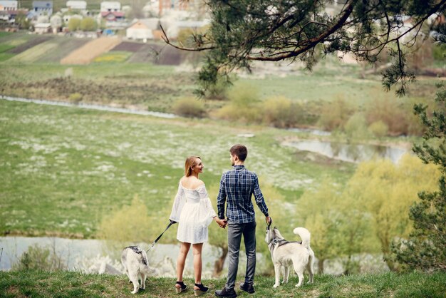 Bonita pareja en un bosque de verano con perros.