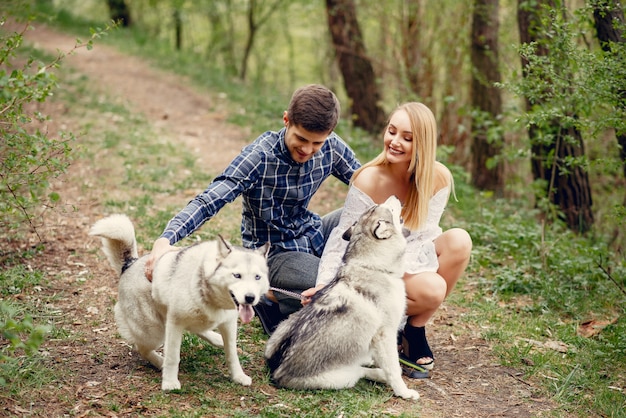 Bonita pareja en un bosque de verano con perros.
