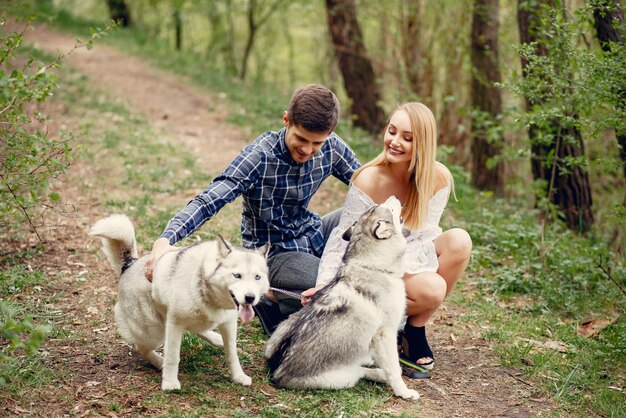 Bonita pareja en un bosque de verano con perros.