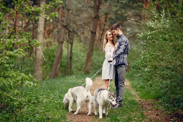 Bonita pareja en un bosque de verano con perros.