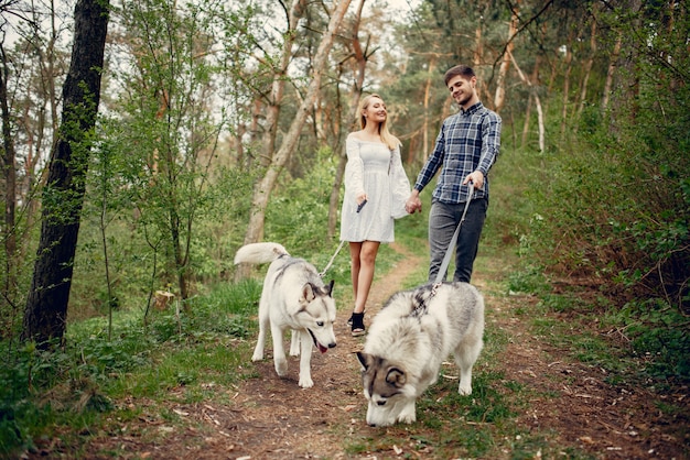 Bonita pareja en un bosque de verano con perros.