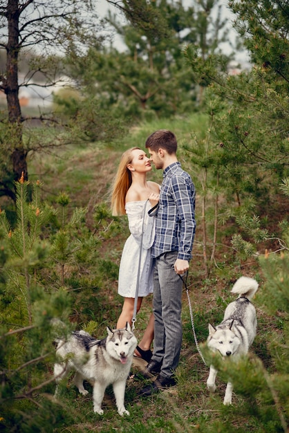 Bonita pareja en un bosque de verano con perros.