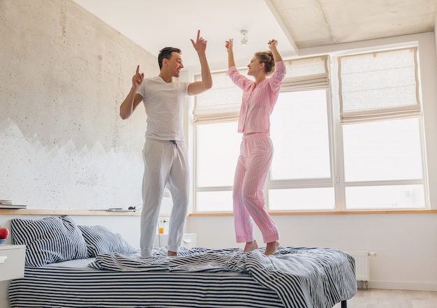 Bonita pareja joven divirtiéndose en la cama por la mañana permanecer juntos en casa solos