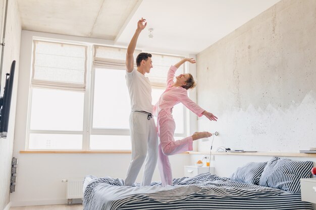 Bonita pareja joven divirtiéndose en la cama por la mañana permanecer juntos en casa solos