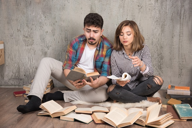 bonita pareja leyendo libros mientras está sentado en el suelo