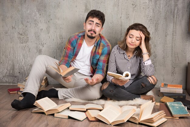 bonita pareja sentada en el suelo con un montón de libros