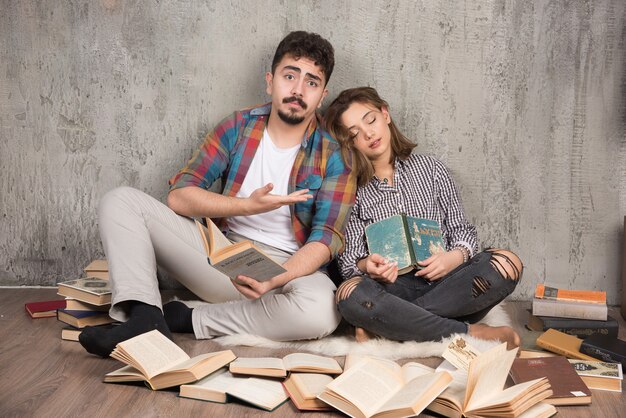 bonita pareja sentada en el suelo con un montón de libros