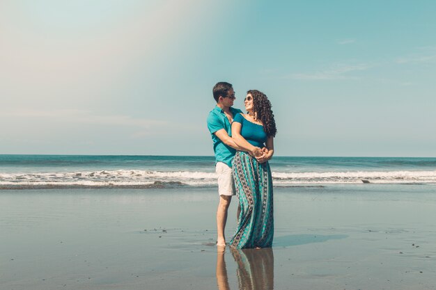 Bonita pareja sonriendo y mirando el uno al otro en la playa