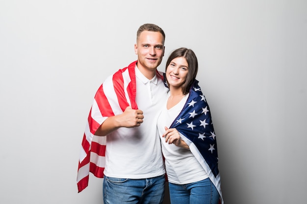 Bonita pareja sonriente sostiene la bandera estadounidense en sus manos, se cubren aislados en blanco