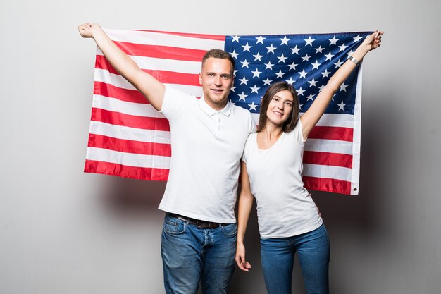 Bonita pareja sostiene la bandera de Estados Unidos en sus manos, se cubren aislados en blanco