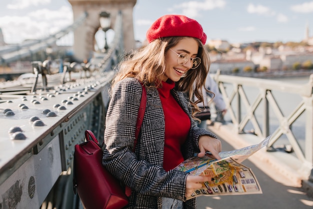 Bonita turista mirando el mapa de la ciudad con una sonrisa