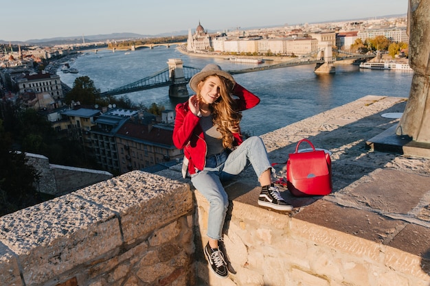 Bonita turista en traje rojo disfrutando de turismo en el país europeo y riendo