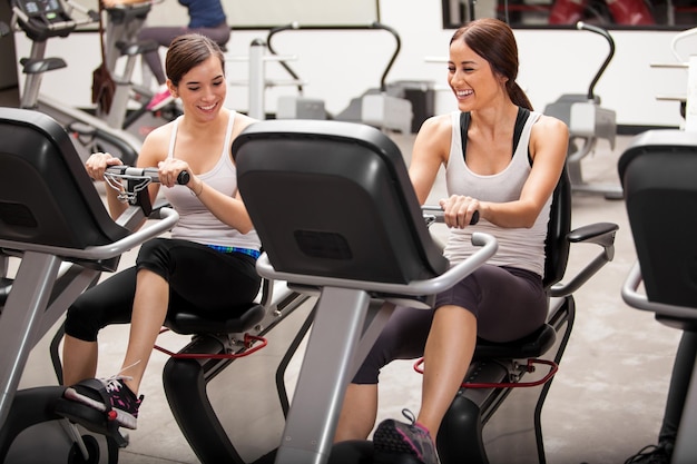 Bonitas amigas hispanas divirtiéndose y trabajando juntas en una clase de spinning