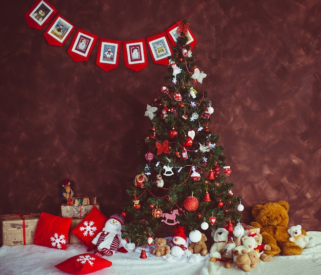 Bonito árbol de Navidad se encuentra ante una pared roja