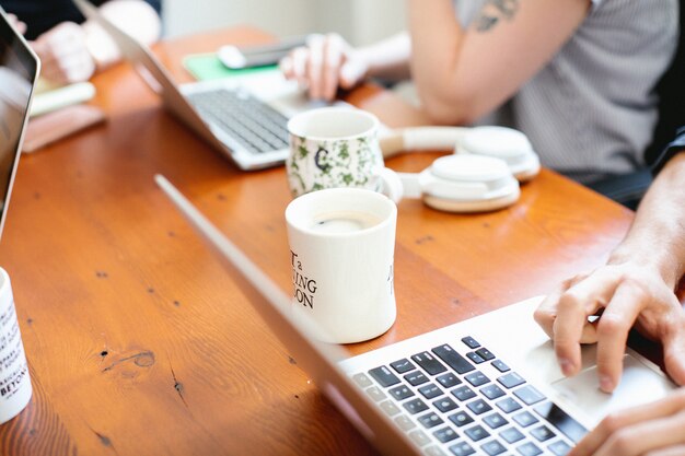 Bonito espacio de trabajo con computadoras portátiles y tazas de café.