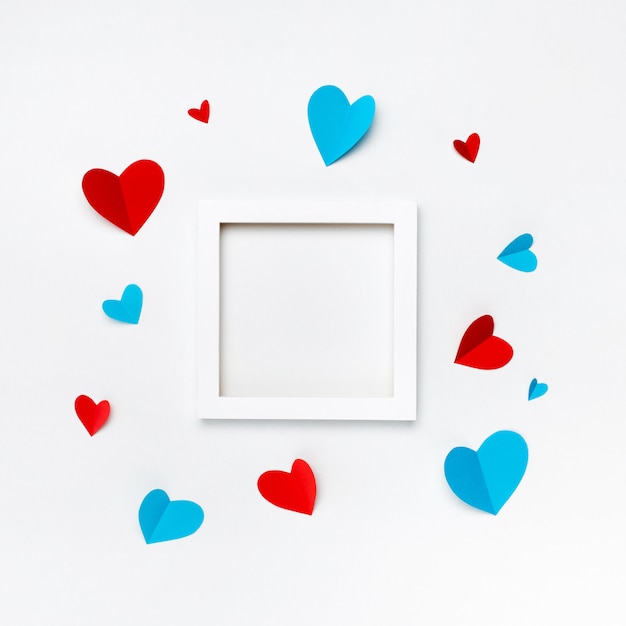 Foto gratuita bonito marco cuadrado blanco con copyspace para texto sobre fondo blanco decorado con corazones de papel hecho a mano