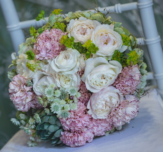 Bonito ramo de flores blancas y rosas de pie sobre una silla blanca