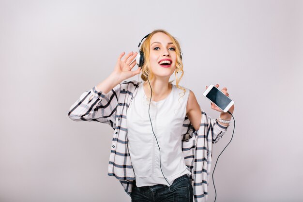 Bonito retrato de mujer hermosa encantada con cabello rubio. Música niña feliz bailando contra el tiempo de fiesta. Ocio. Estilo de vida positivo activo