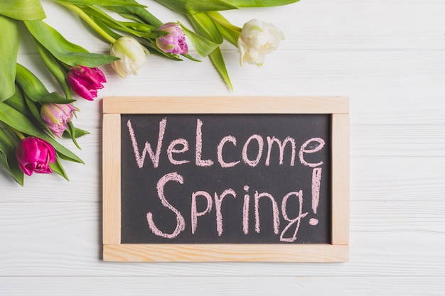 Foto gratuita bonitos tulipanes cerca de la escritura de welcome spring