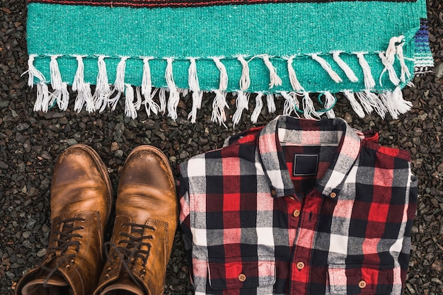 Foto gratuita botas y camisa cerca de la manta