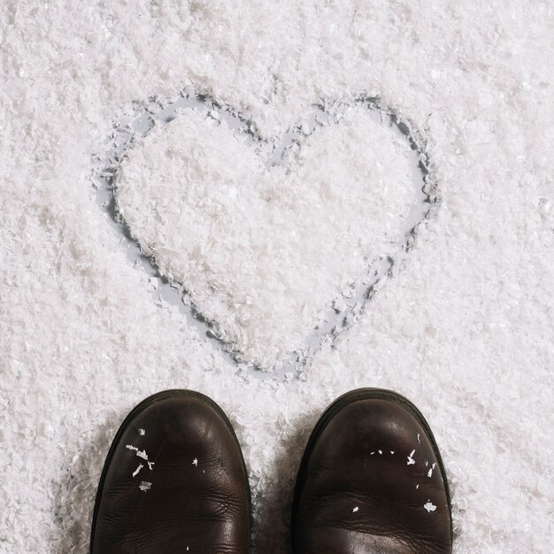 Botas cerca de corazón pintado sobre nieve.