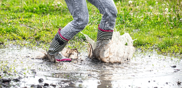 Foto gratuita botas de goma en un charco en el proceso de saltar con salpicaduras de agua