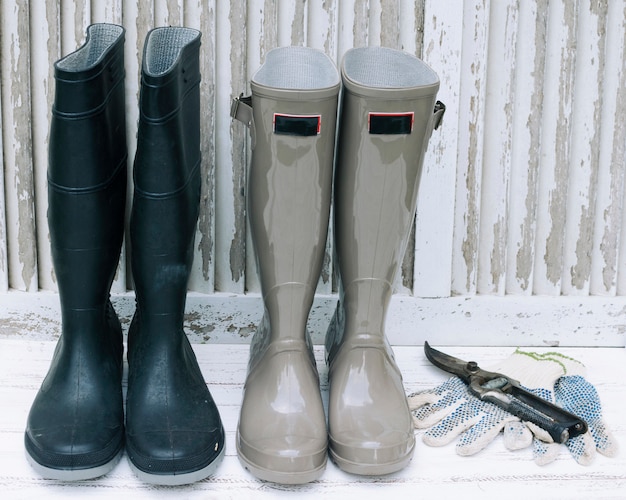 Botas impermeables y podadora en madera blanca.