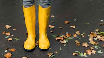 Foto gratuita botas de lluvia junto a hojas de otoño