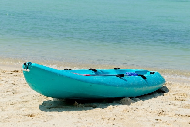 Bote de remos azul en la playa con el hermoso océano de fondo