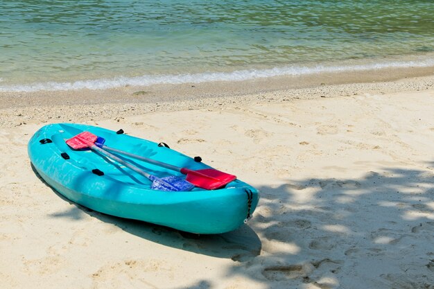 Bote de remos azul en la playa con el hermoso océano