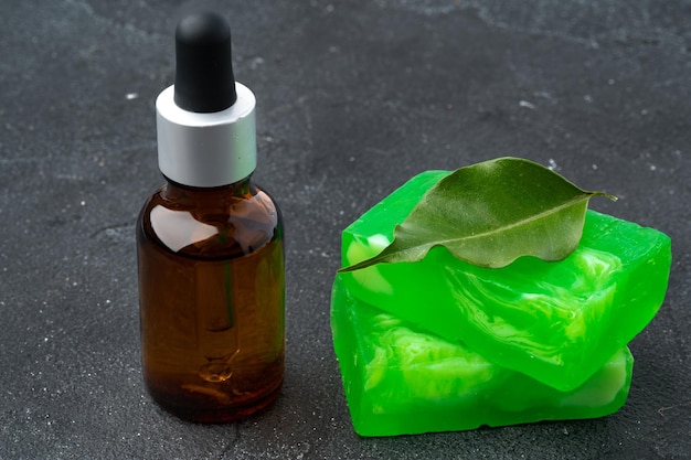 Botella de aceite esencial de eucalipto y barras de jabón sobre fondo negro