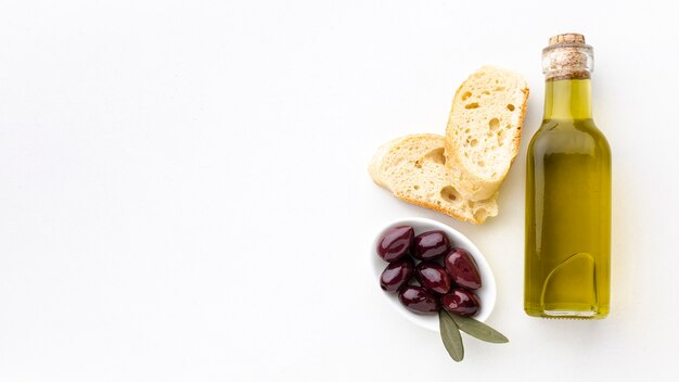 Botella de aceite de oliva rebanadas de pan y aceitunas moradas con espacio de copia