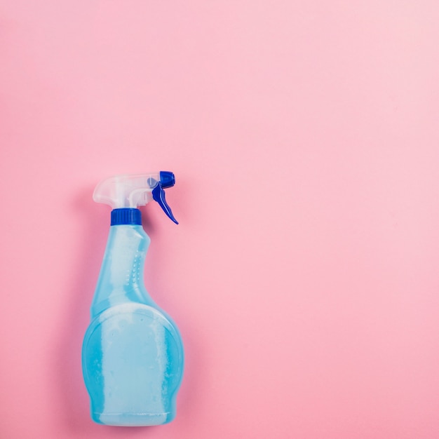 Botella de aerosol azul sobre fondo rosa