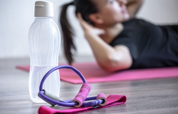 Botella de agua y una banda elástica para fitness sobre un fondo borroso.