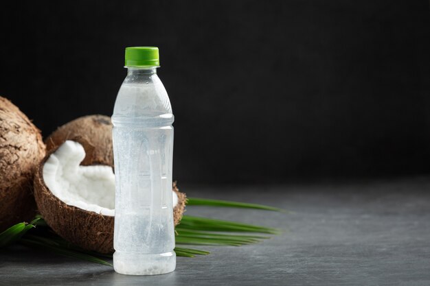 Botella de agua de coco sobre fondo oscuro