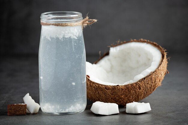 Botella de agua de coco sobre fondo oscuro