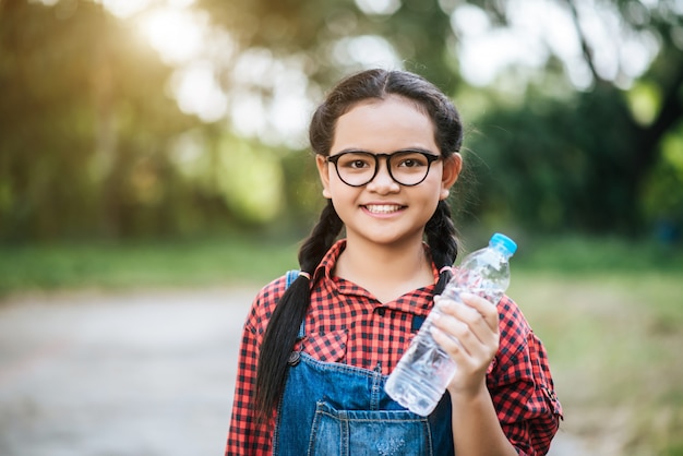 Botella de agua plástica en mano de niña