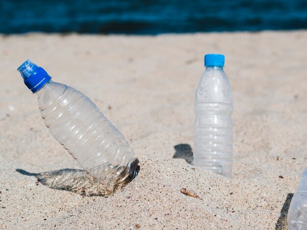 Botella de agua de plástico vacía en la arena en la playa