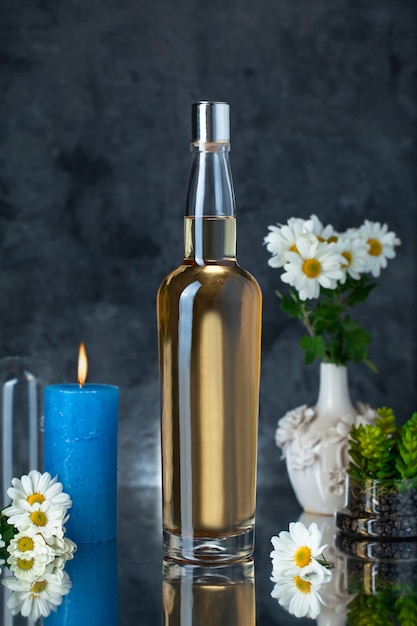 Botella de alcohol con flores y velas.